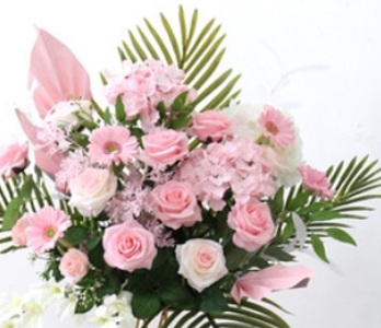 Pink roses gerberas carnations with areca palm leaves in basket arrangement